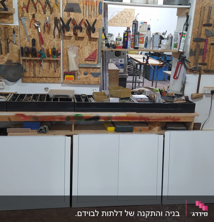 סדנת נגרות עם כלים על הקיר ושולחן עבודה